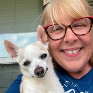 Blonde female wearing glasses smiling holding a Chihuahua named Uno